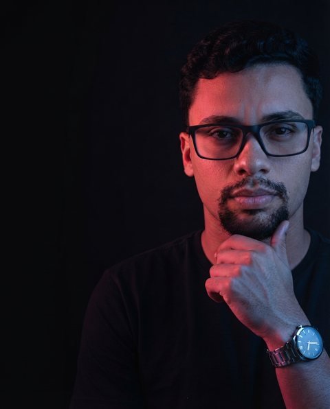 Rodrigo Ribeiro, mentor de Meta Ads, de óculos e camiseta escura, com a mão no queixo.